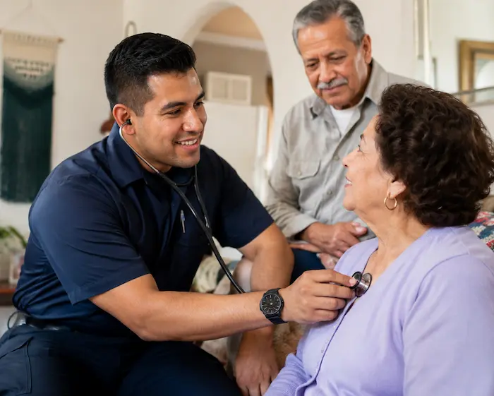 Healthcare professional checking an older adult patient's blood pressure during an in-home wellness visit.